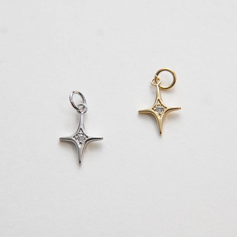 May include: Two star-shaped charms with a single clear stone in the center. One charm is silver and the other is gold.