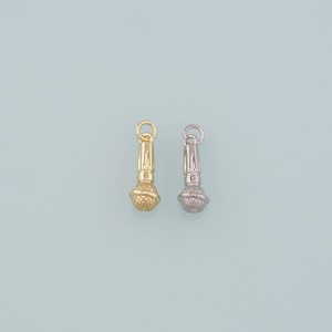 May include: Two microphone-shaped charms. One is gold-colored, the other is silver-colored. Both have a textured, spherical base and a loop at the top for attaching to a necklace or bracelet. The background is a light blue.