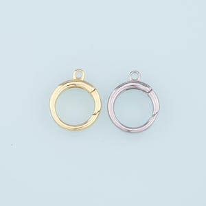 May include: Two metal key rings, one gold and one silver, with a small loop at the top. The rings are open and have a spring-loaded clasp.