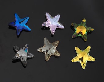 May include: Six star-shaped crystal beads in various colors: blue, lavender, green, gray, tan, and yellow. Each bead has multiple facets, creating a sparkling effect. The beads are arranged on a dark surface.