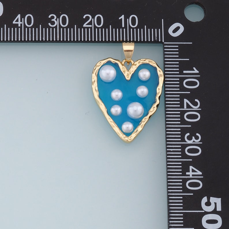 May include: A gold heart-shaped pendant with a blue enamel finish and white pearl accents.