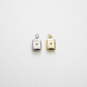 May include: Two small rectangular pendants with a star-shaped diamond in the center. One pendant is silver and the other is gold.