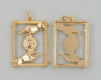May include: Two gold-toned pendants with a geometric design. Each pendant features a stylized hand reaching towards a sun with an eye in the center. The pendants are framed with a decorative border.