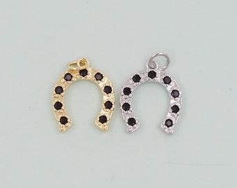 May include: Two gold and silver horseshoe charms with black cubic zirconia stones. The charms are perfect for jewelry making or adding a touch of luck to your projects.