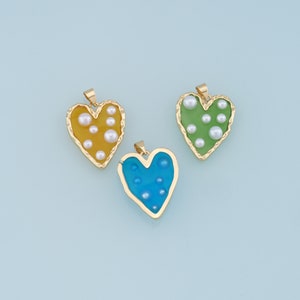 May include: Three gold heart-shaped pendants with different colored resin inserts and white pearl accents. The pendants are yellow, green, and blue.
