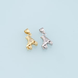 May include: Two roller skate charms, one gold and one silver, with clear rhinestones. The charms are on a white background.