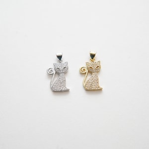 May include: Two silver and gold cat pendants with clear crystal accents. The pendants are in the shape of a sitting cat with a curled tail.
