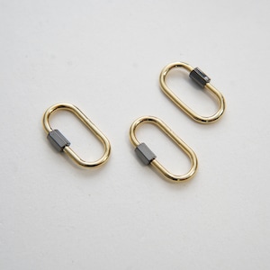 Puede incluir: Tres llaveros ovalados de color dorado con un cierre de metal negro.