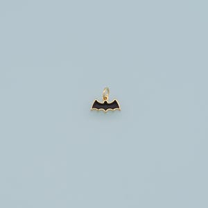 May include: A gold-colored charm in the shape of a black bat.