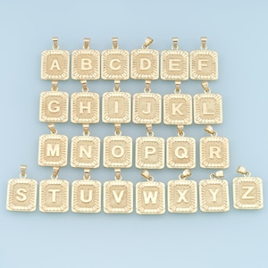 May include: A set of 26 gold-tone pendants, each featuring a different letter of the alphabet in a square frame. The pendants are arranged in alphabetical order.