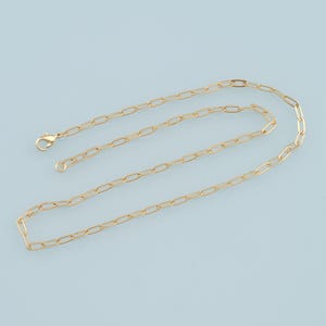 May include: A gold chain necklace with a delicate, linked design. The chain is made of small, oval-shaped links.