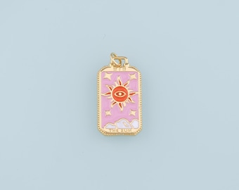 May include: Gold-toned pendant charm featuring a pink and orange enamel design of the sun with a single eye in the center. The charm is rectangular with a beaded border and the words "THE SUN" at the bottom.