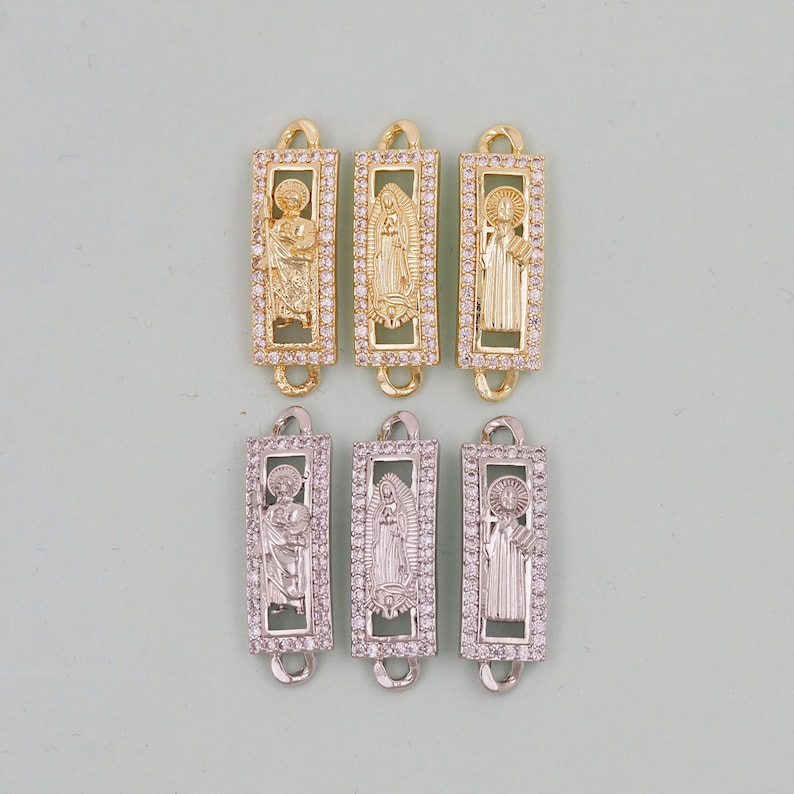 May include: Six gold and silver charm pendants featuring religious figures. Each pendant has a rectangular frame with clear rhinestones and a raised image of a saint. The pendants are ideal for adding a touch of faith to jewellery.