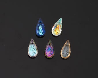 May include: Five teardrop-shaped crystal pendants in various colors: blue, iridescent, light blue, purple, and amber. Each pendant has a faceted surface, catching and reflecting light. The pendants are arranged on a dark background.