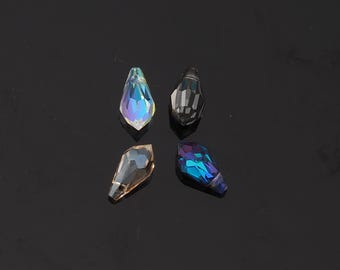 May include: Four iridescent teardrop-shaped crystal beads. The beads have a faceted design, reflecting a spectrum of colors including blue, purple, and gold. They are arranged against a dark background, highlighting their sparkle and clarity.