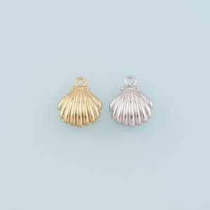 Puede incluir: Dos abalorios de concha, uno dorado y otro plateado, con un bucle en la parte superior para sujetar a las joyas.