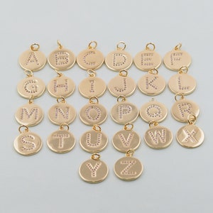 May include: A set of 26 gold-toned charms, each featuring a different letter of the alphabet, adorned with pink rhinestones. The charms are perfect for adding a personalized touch to jewelry or crafts.