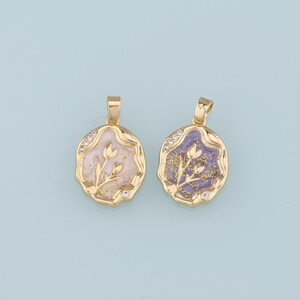 May include: Two gold pendants with a flower design. The pendant on the left has a white background with gold glitter and the pendant on the right has a purple background with gold glitter.