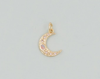 May include: A gold crescent moon charm with a clear opal stone in the center and small clear rhinestones around the edge.