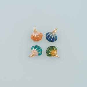 May include: Four gold-colored shell charms with enamel paint in different colors: orange, blue, green, and yellow. The charms are on a light blue background.
