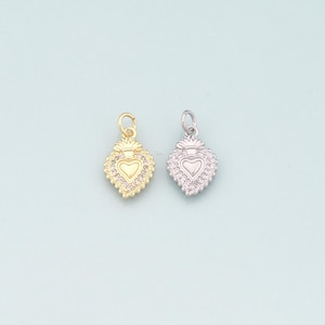 May include: Two heart-shaped pendants, one gold-toned and one silver-toned, each adorned with small, clear gemstones. The pendants feature a heart design in the center and a decorative crown at the top, perfect for jewelry making.