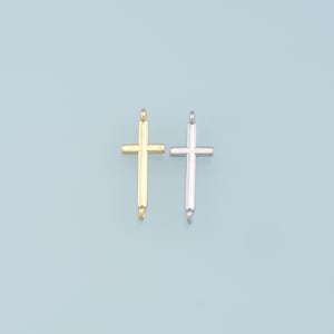 Puede incluir: Dos dijes de cruz de metal, uno dorado y otro plateado, con un bucle en la parte superior para sujetar a un collar o pulsera.