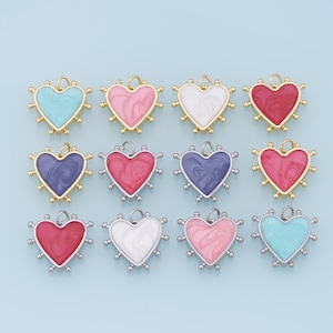 以下が含まれることがあります： 金と銀のアクセントが付いたハート型のチャームが12個。チャームはピンク、ブルー、ホワイト、レッドなど、さまざまな色があります。各チャームの上部には、ネックレスやブレスレットに取り付けるための小さなループが付いています。