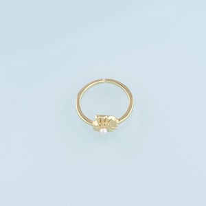 May include: A gold ring with a delicate pearl and a sun-shaped design.