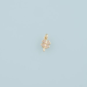 May include: A gold four-leaf clover charm with clear sparkling stones.