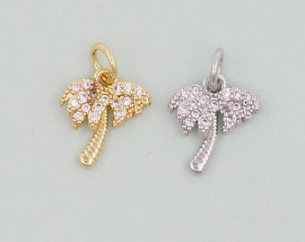 May include: Two palm tree charms, one gold and one silver, with clear crystal accents.