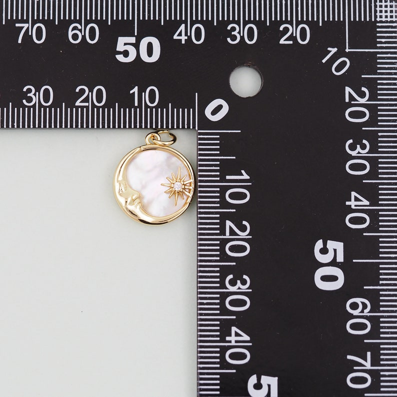 May include: A gold-tone pendant featuring a crescent moon with a face and a star with a clear rhinestone in the center. The moon is made of white mother-of-pearl. The pendant is approximately 1.5 inches in diameter.
