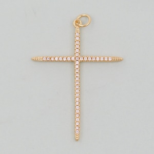 May include: A gold-colored cross pendant with a loop at the top for a chain. The cross is adorned with small, sparkling, clear gemstones. The design is symmetrical, with pointed ends on each arm.