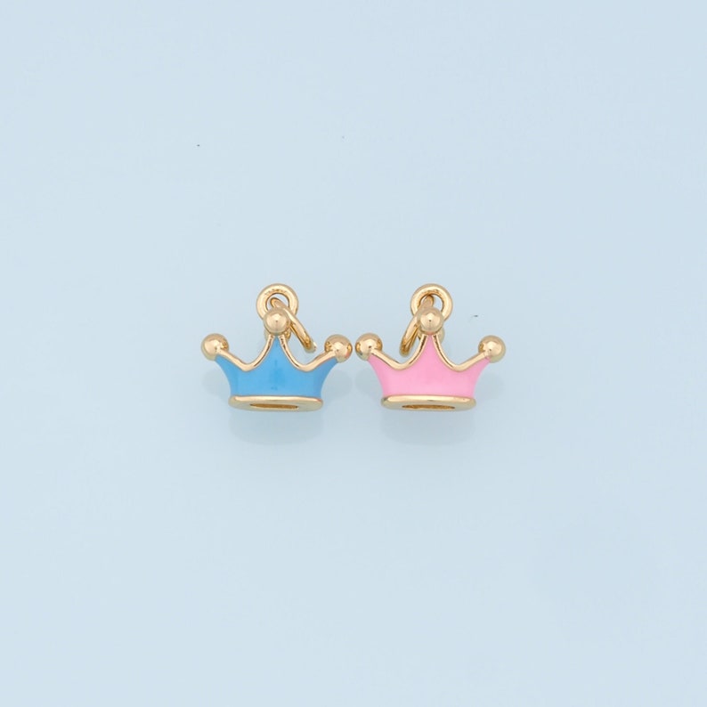 May include: Two gold crown charms, one with light blue enamel and one with pink enamel.