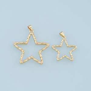 May include: Two gold-toned star-shaped pendants. The larger pendant is slightly textured and has a more intricate design. The smaller pendant is smooth and has a simpler design.