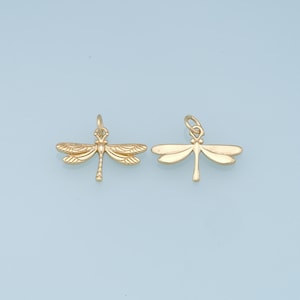 May include: Two gold-colored dragonfly charms with detailed wings and a loop for attaching to jewelry.
