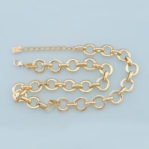 May include: A gold-colored chain necklace with large, circular links. The necklace has an adjustable length with a lobster clasp closure. The design is simple and elegant, suitable for various occasions.