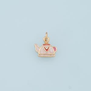 Puede incluir: Encanto de oro en forma de tetera blanca con detalles rojos y rosas.