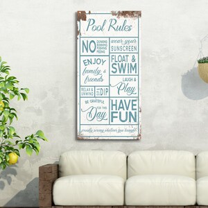 May include: A white sign with blue text that reads "Pool Rules" and lists rules for pool behavior. The sign is hanging on a white wall next to a white couch and a potted lemon tree.