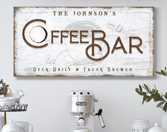 May include: A white wooden sign with brown text that reads "The Johnson's Coffee Bar Open Daily & Fresh Brewed". The sign is hanging on a wall above a coffee bar setup with a coffee maker, mugs, and other coffee-related items.