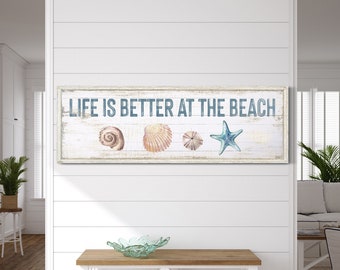 May include: A white wooden sign with the text "Life is better at the beach" in blue lettering. The sign is decorated with seashells and a starfish.
