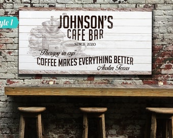 May include: White wooden sign with black text that reads "JOHNSON'S CAFE BAR SINCE 2020" and "Therapy in a cup COFFEE MAKES EVERYTHING BETTER Austin Texas". The sign has a vintage coffee grinder illustration.