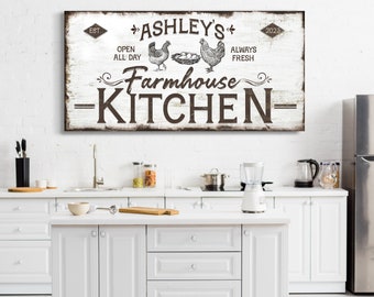 Op de afbeelding: Een wit boerderijkeukenbord met zwarte tekst die "Ashley's Farmhouse Kitchen" luidt, met de woorden "Est." en "2023" in de bovenhoeken. Het bord bevat ook de woorden "Open All Day" en "Always Fresh" met een afbeelding van drie kippen en een nest met eieren.