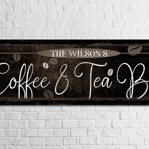 May include: A rustic wooden sign with the text "The Wilson's Coffee & Tea Bar" in white cursive lettering. The sign is decorated with brown coffee beans and has a distressed, vintage look.