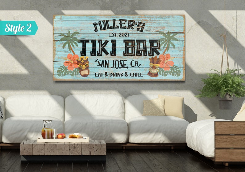 K&ouml;nnte beinhalten: Ein blaues und wei&szlig;es Holzschild mit dem Text "MILLER'S EST. 2021 TIKI BAR SAN JOSE, CA EAT & DRINK & CHILL". Das Schild hat ein tropisches Thema mit Palmen, Blumen und Tiki-Masken.