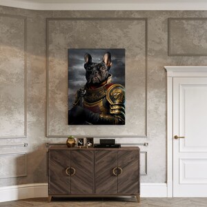May include: A framed canvas print featuring a black French Bulldog in golden armor, set against a dark, cloudy backdrop. The dog is depicted in a regal pose, holding a small object, with a stern expression. The artwork is displayed above a wooden cabinet.