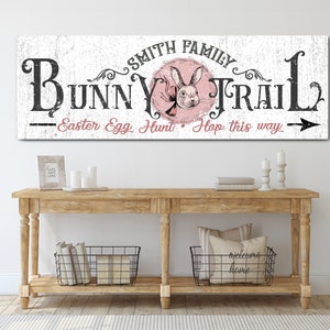 May include: A white wooden sign with black text that reads "Smith Family Bunny Trail - Easter Egg Hunt - Hop this way" with a pink bunny rabbit illustration in the center.