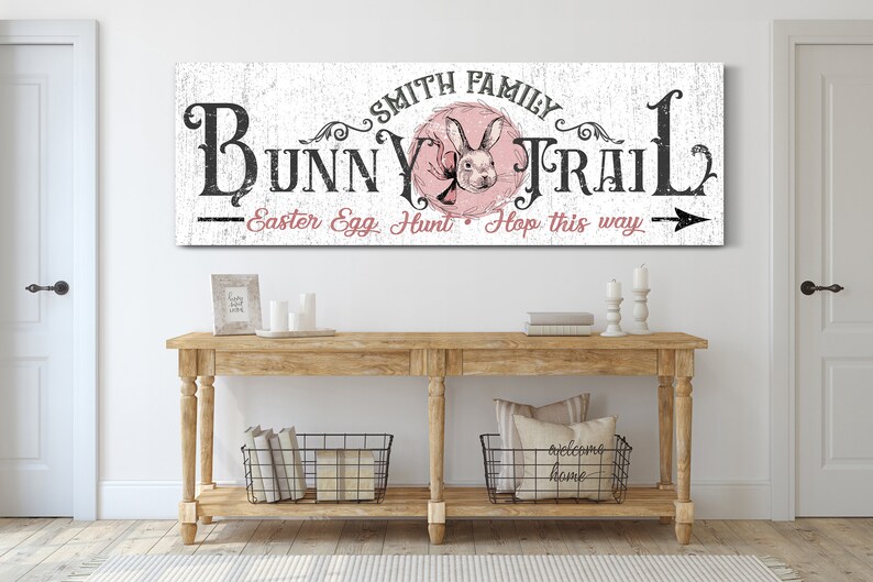May include: A white wooden sign with black text that reads "Smith Family Bunny Trail - Easter Egg Hunt - Hop this way" with a pink bunny rabbit illustration in the center.