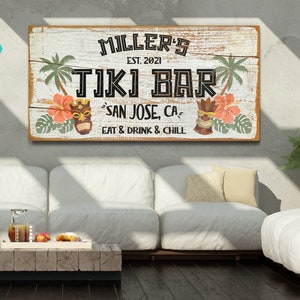 K&ouml;nnte beinhalten: Ein rustikales Holzschild mit dem Text "MILLER'S EST. 2021 TIKI BAR SAN JOSE, CA EAT & DRINK & CHILL". Das Schild zeigt Palmen, tropische Blumen und Tiki-Masken.