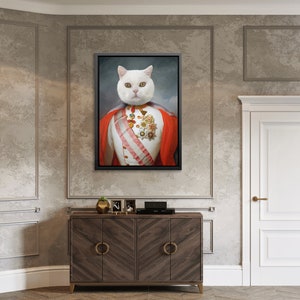 May include: A framed canvas print featuring a regal white cat portrait. The cat is dressed in a red and white military-style uniform with gold medals and a striped sash. The artwork is displayed above a wooden cabinet.