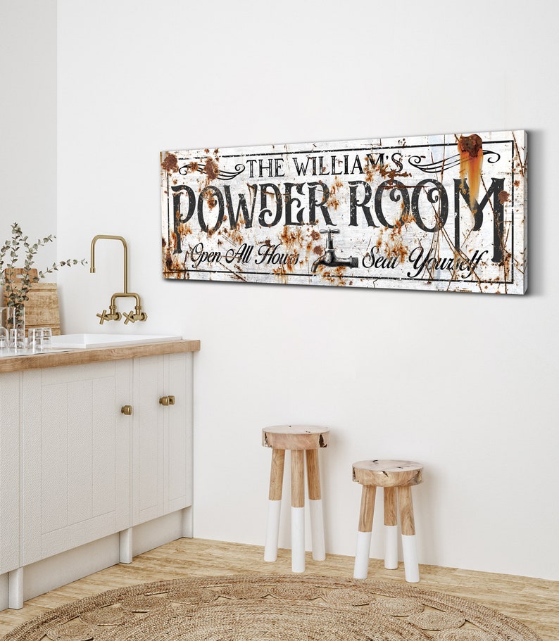 May include: Rustic white sign with black text that reads "The William's Powder Room Open All Hours Seat Yourself". The sign has a distressed look with rust accents.